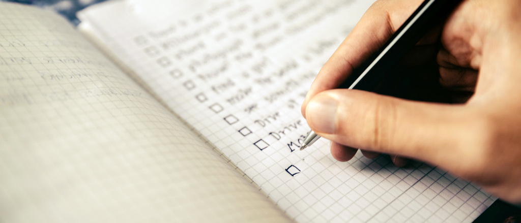 A hand checking item off of a paper checklist.